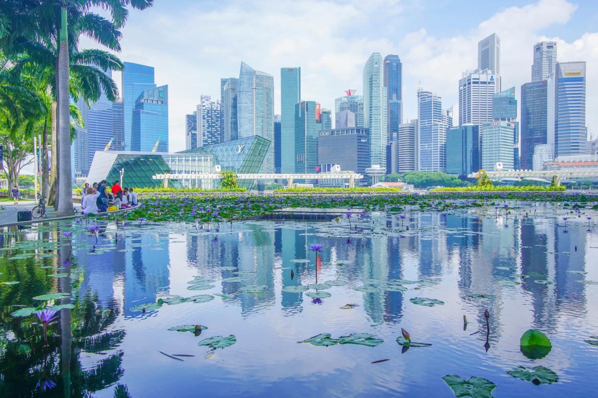 People relaxing near a waterfront in Singapore with commercial buildings in the background