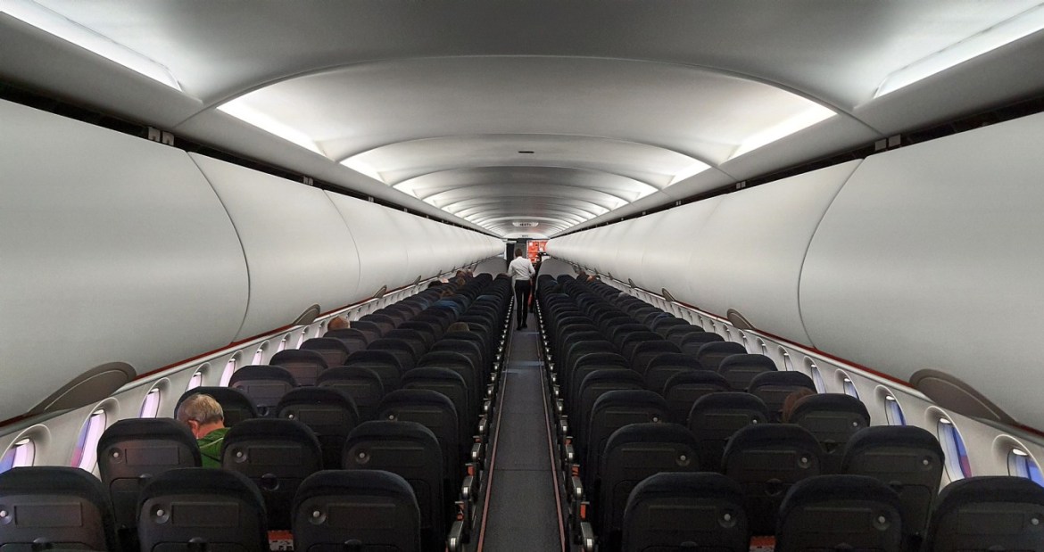 A flight attendant walking past rows of empty seats in an airplane